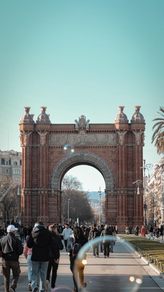 A group of people walking in front of a large arch barcelona