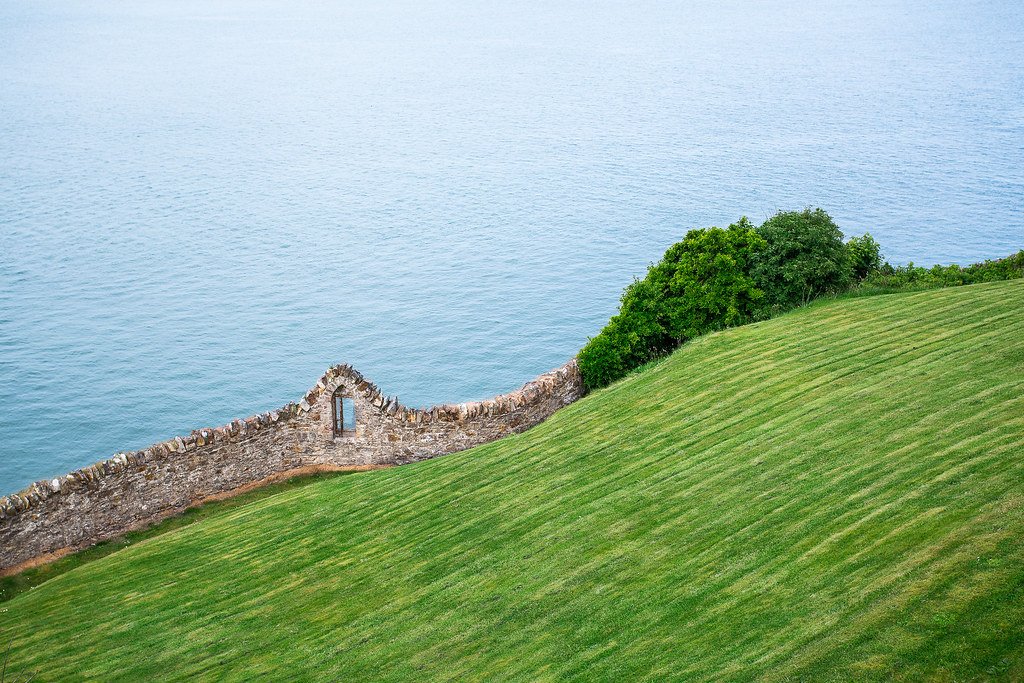Vista aérea da trilha de Howth com penhascos cobertos de vegetação e o mar azul profundo ao lado