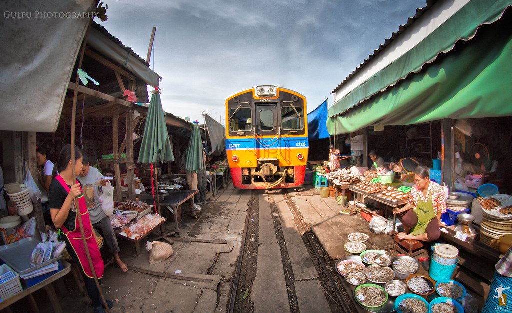 Trem passando rente às barracas recolhidas no Maeklong Railway Market em Bangkok