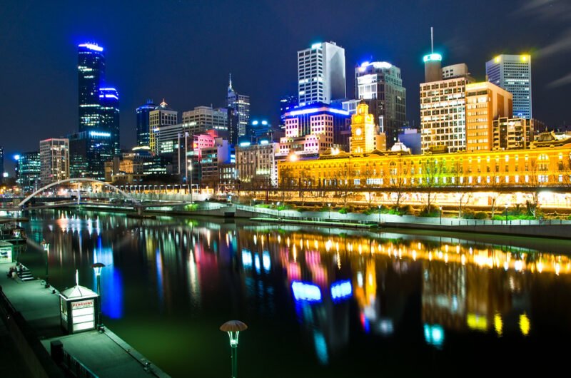 Melbourne Australia a noite com a cidade acesa com um corpo de água na frente