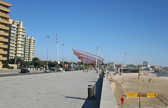 Praia de Matosinhos com areia dourada e o sol se pondo no horizonte atlântico
