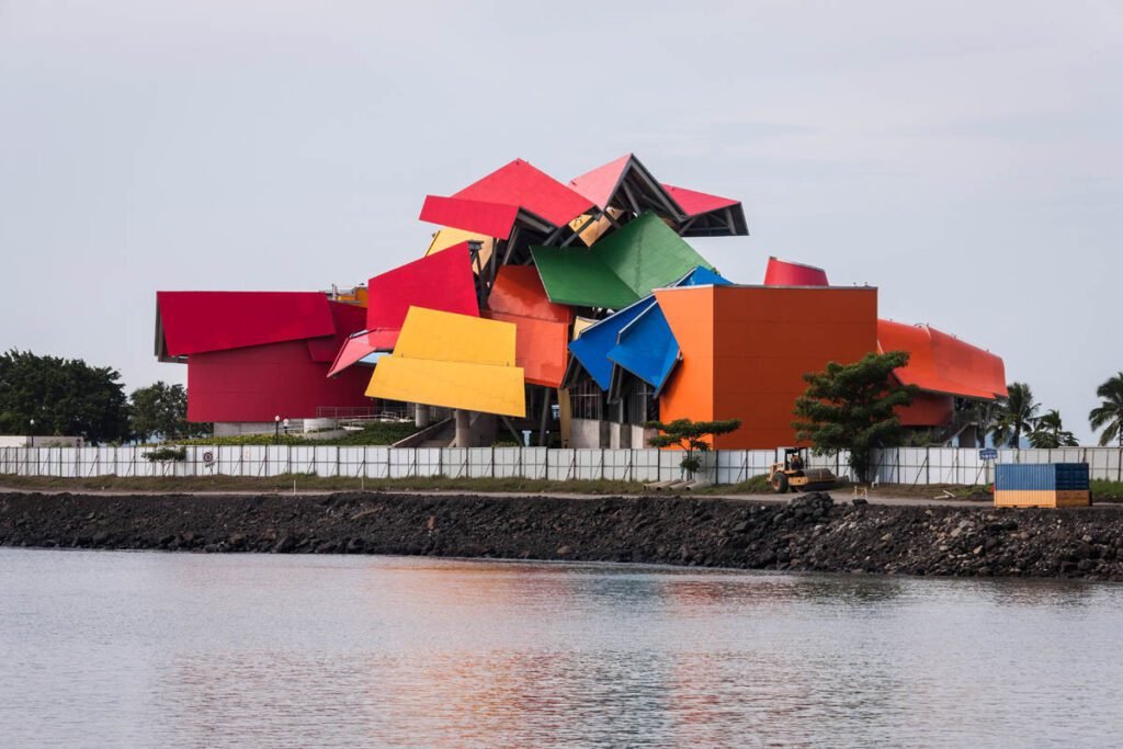 Fachada colorida e geométrica do Biomuseo ao lado da baía, em dia nublado panamá